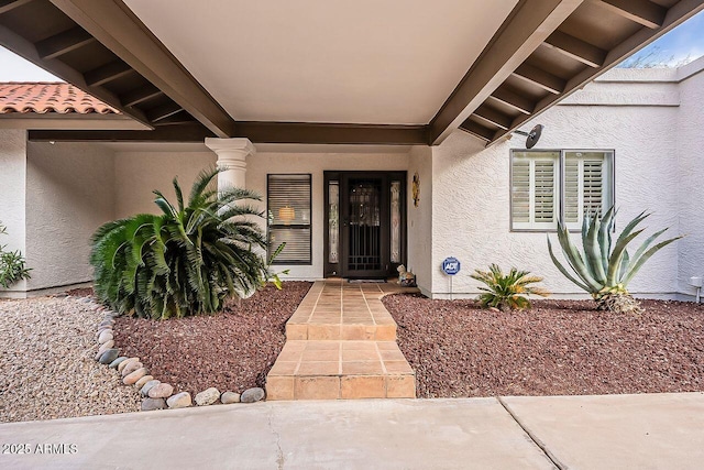 entrance to property with a tile roof and stucco siding