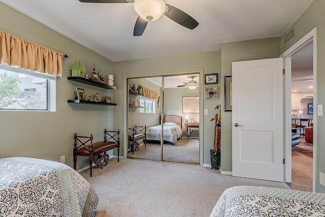 carpeted bedroom featuring baseboards, visible vents, arched walkways, ceiling fan, and a closet