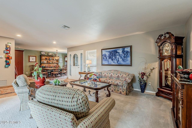 living room with light carpet, visible vents, and baseboards