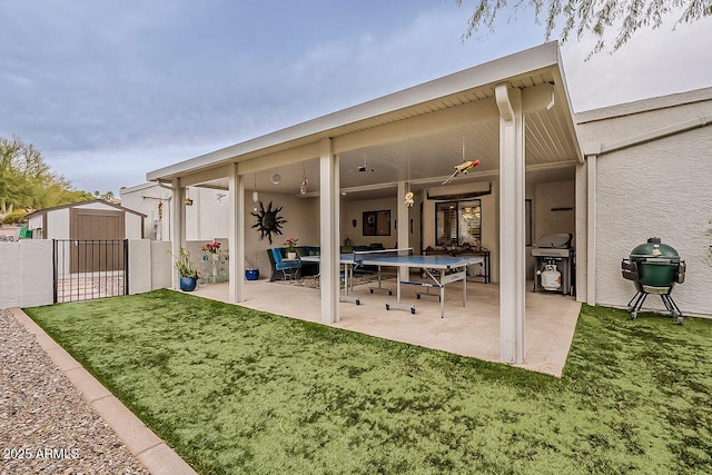 back of property featuring a lawn, a patio, an outbuilding, a shed, and stucco siding