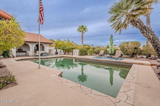 outdoor pool featuring a patio area, a fenced backyard, and a fireplace