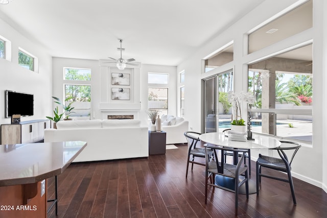 dining room with ceiling fan, a large fireplace, and dark hardwood / wood-style floors