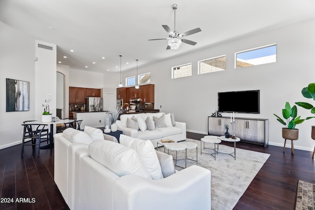 living room with a towering ceiling, dark hardwood / wood-style flooring, and ceiling fan