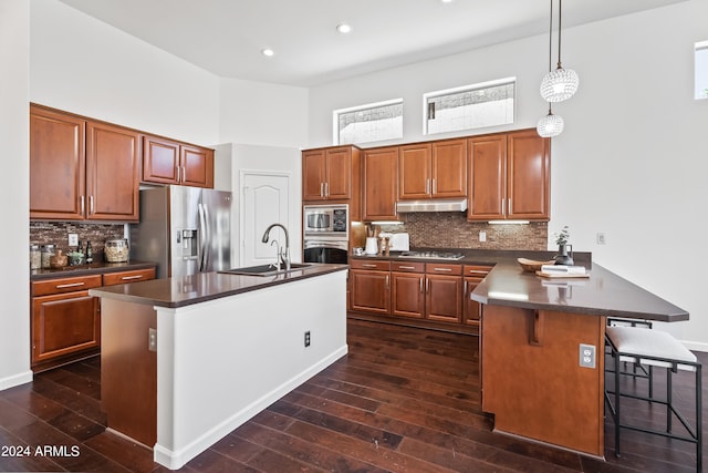 kitchen with stainless steel appliances, dark hardwood / wood-style flooring, kitchen peninsula, a towering ceiling, and pendant lighting