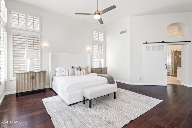 bedroom with a barn door, dark wood-type flooring, and multiple windows
