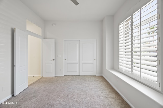 unfurnished bedroom with light colored carpet and a closet