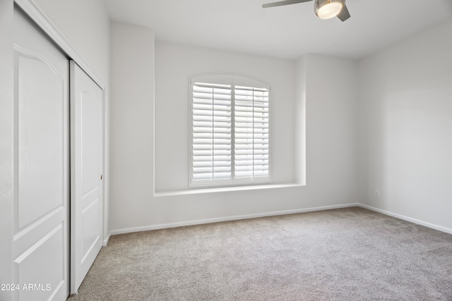 unfurnished bedroom featuring ceiling fan, a closet, and light colored carpet