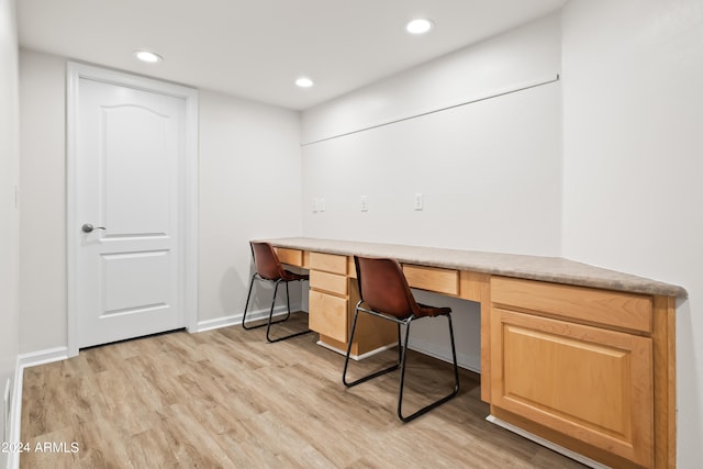 unfurnished office with built in desk and light hardwood / wood-style flooring