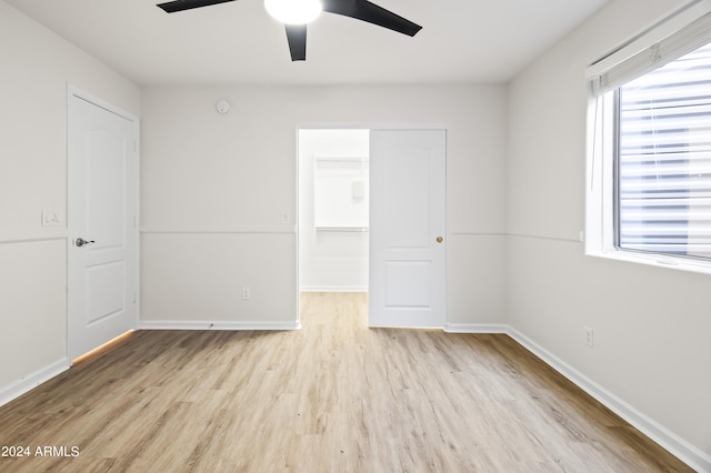 unfurnished bedroom with ceiling fan, a closet, light hardwood / wood-style floors, and a spacious closet