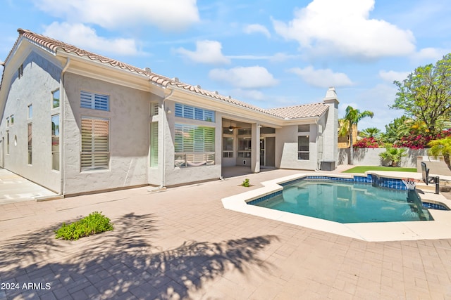 rear view of property with a patio area and a pool with hot tub