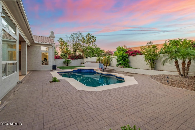 pool at dusk featuring a patio