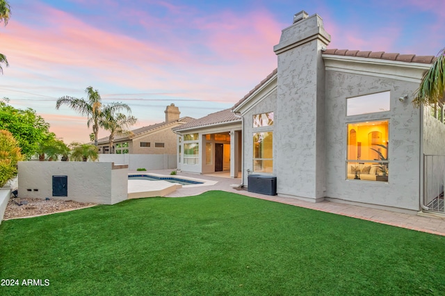 back house at dusk with a fenced in pool, a patio area, a yard, and central AC unit