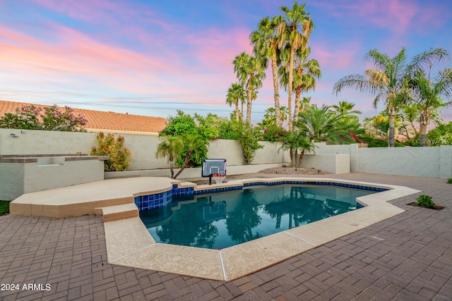 pool at dusk featuring a patio
