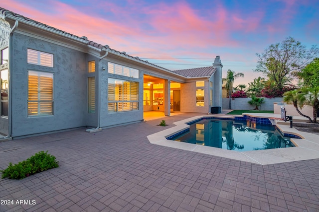 pool at dusk featuring a patio