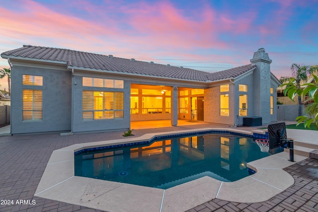 pool at dusk featuring a patio