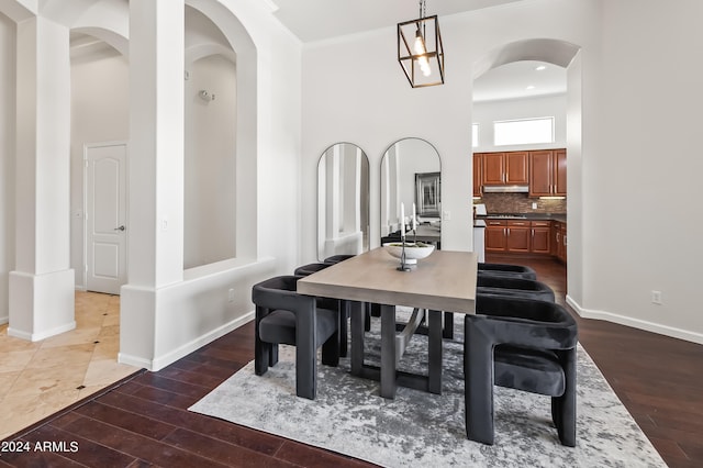 dining area with dark hardwood / wood-style flooring, a towering ceiling, a chandelier, and ornamental molding