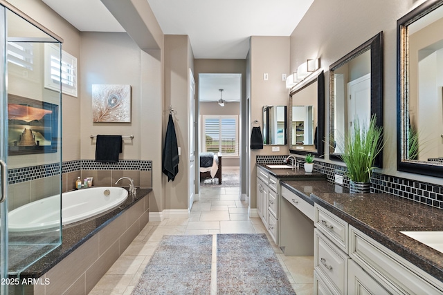 bathroom with a relaxing tiled tub, vanity, and tile patterned flooring