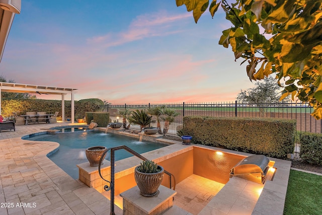 pool at dusk with a patio, pool water feature, and area for grilling