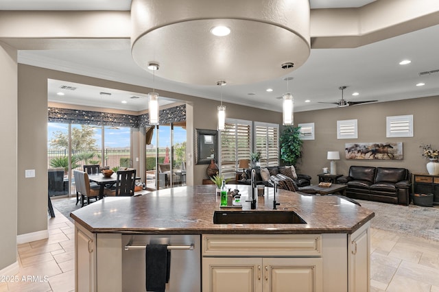 kitchen featuring pendant lighting, sink, a kitchen island with sink, ornamental molding, and dark stone counters