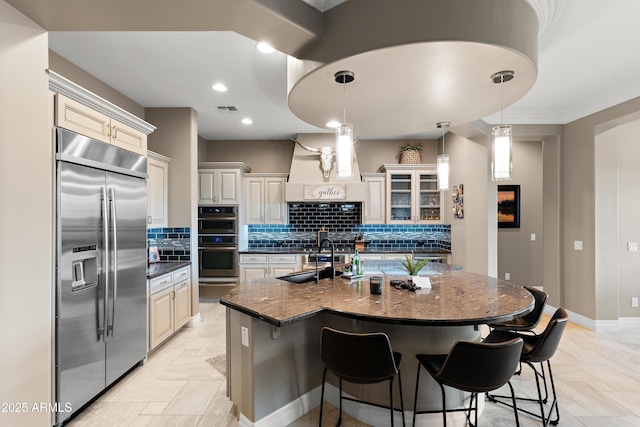 kitchen featuring sink, dark stone countertops, decorative backsplash, a kitchen island with sink, and stainless steel appliances