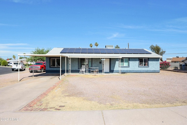 single story home featuring solar panels, a carport, and a porch