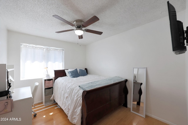 bedroom featuring a textured ceiling, light hardwood / wood-style flooring, and ceiling fan