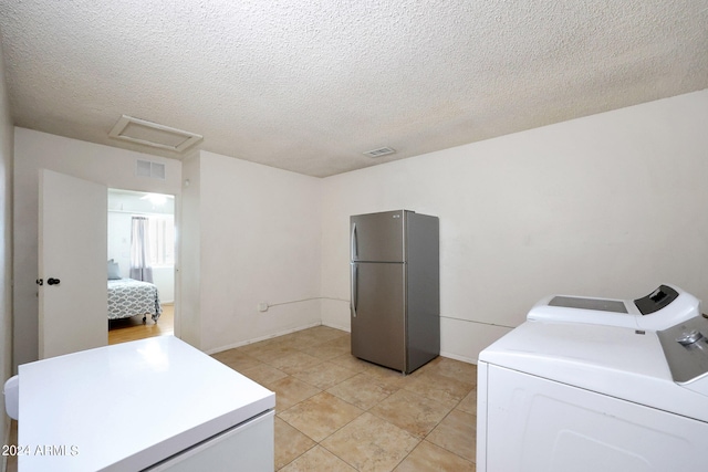 laundry room with separate washer and dryer, a textured ceiling, and light tile patterned floors