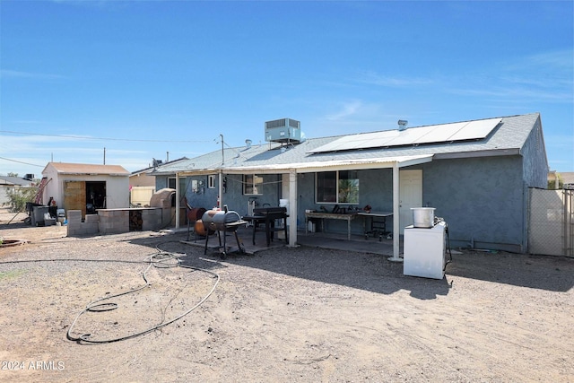 back of property with central air condition unit, a patio, and solar panels