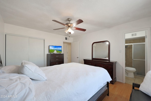 bedroom featuring light hardwood / wood-style flooring, a closet, ceiling fan, connected bathroom, and a textured ceiling