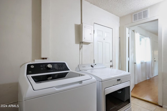 washroom featuring light tile patterned floors, a textured ceiling, and washer and dryer