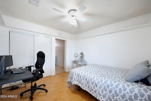 bedroom featuring a textured ceiling, light hardwood / wood-style flooring, ceiling fan, and a closet