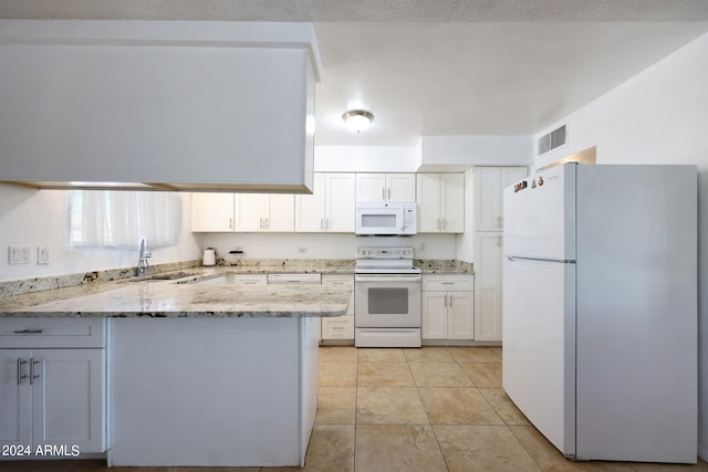 kitchen featuring white appliances, light stone countertops, white cabinetry, sink, and kitchen peninsula