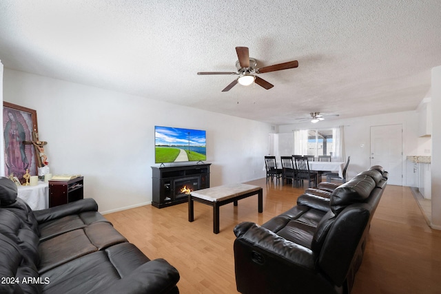 living room featuring a textured ceiling, ceiling fan, and light hardwood / wood-style floors