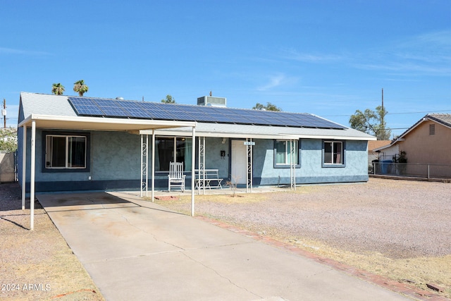 ranch-style house with a porch and solar panels