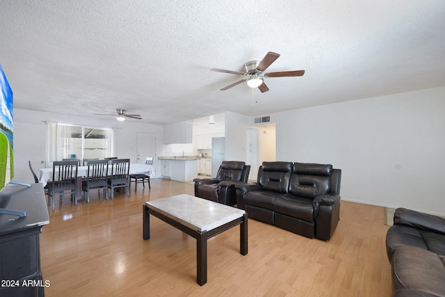 living room featuring a textured ceiling, ceiling fan, and light hardwood / wood-style floors