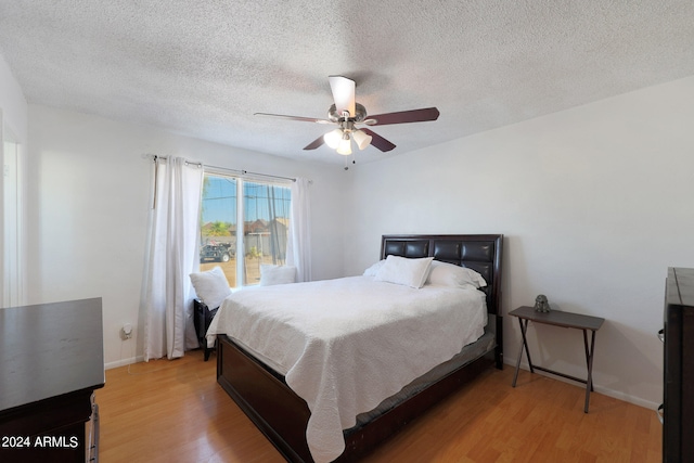 bedroom with ceiling fan, hardwood / wood-style flooring, and a textured ceiling