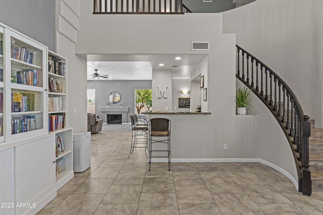 1244 W Straford Ave, Gilbert, AZ 85233 - kitchen with a towering ceiling, a fireplace, ceiling fan, baseboards, and a kitchen breakfast bar