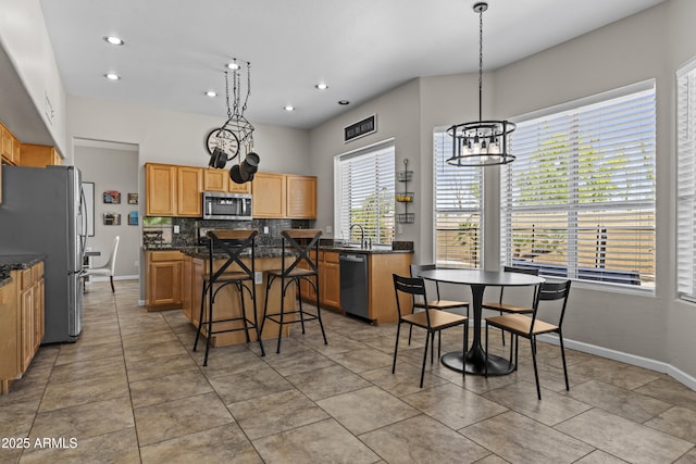 1244 W Straford Ave, Gilbert, AZ 85233 - kitchen featuring stainless steel appliances, a sink, decorative backsplash, a kitchen island, and a kitchen breakfast bar