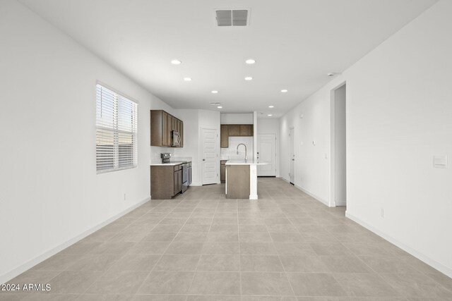 unfurnished living room featuring light tile patterned flooring and sink