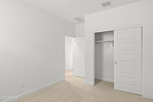 unfurnished bedroom with light carpet and a closet