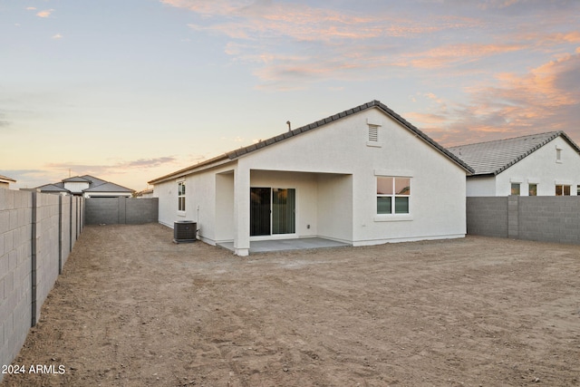 back house at dusk with cooling unit and a patio area