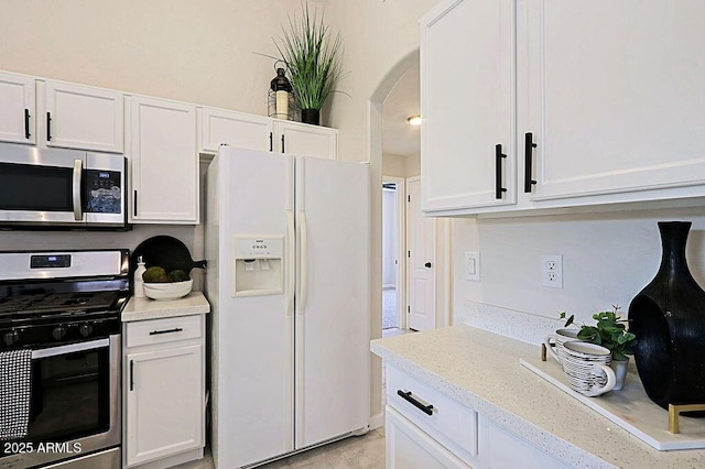 kitchen with light stone counters, appliances with stainless steel finishes, and white cabinets