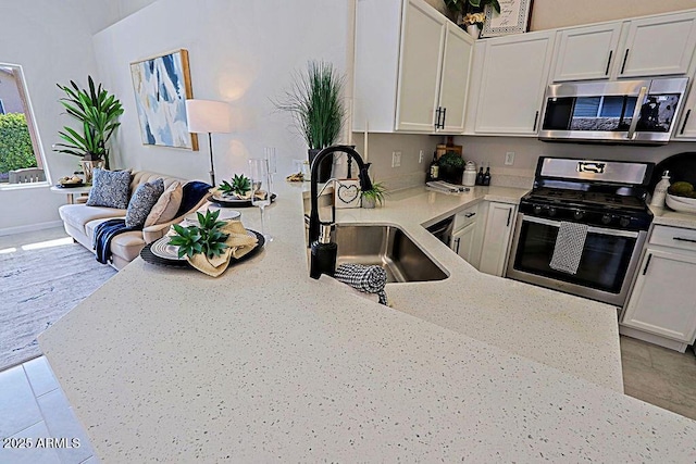 kitchen featuring white cabinetry, sink, light stone counters, and appliances with stainless steel finishes