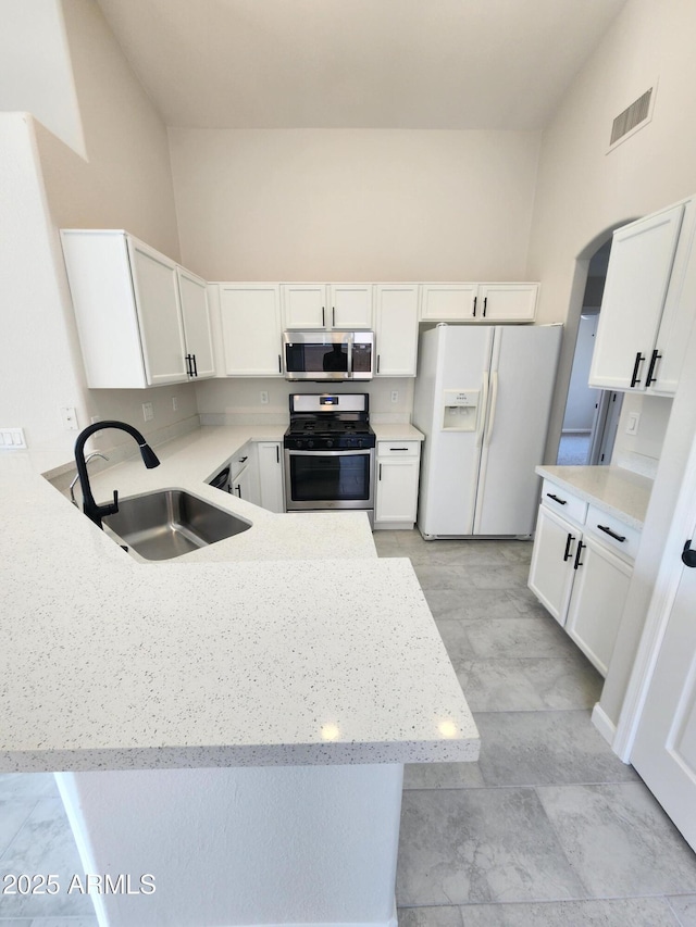 kitchen with appliances with stainless steel finishes, sink, white cabinets, and kitchen peninsula