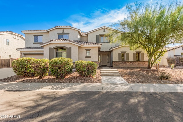 mediterranean / spanish home with stucco siding, an attached garage, and a tiled roof