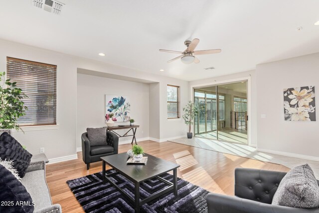 living room with baseboards, ceiling fan, visible vents, and light wood-style flooring