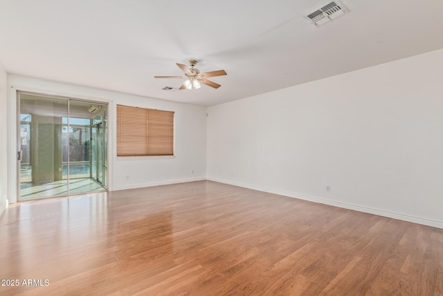 empty room with baseboards, light wood finished floors, ceiling fan, and visible vents