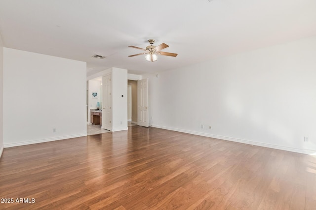 spare room featuring visible vents, baseboards, ceiling fan, and wood finished floors