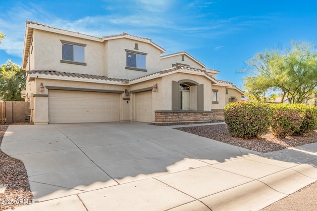 mediterranean / spanish home featuring concrete driveway, a tiled roof, an attached garage, and stucco siding