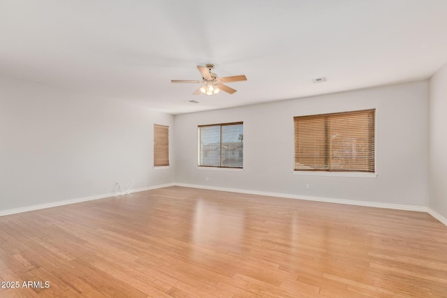 spare room featuring baseboards, light wood finished floors, and ceiling fan